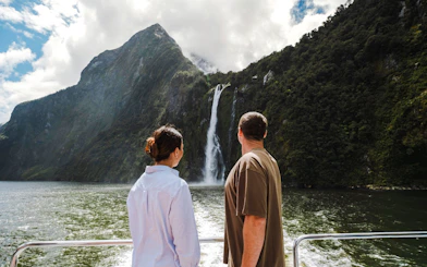 Couple on Milford Sound cruise viewing waterfall, part of Te Anau small group tour.