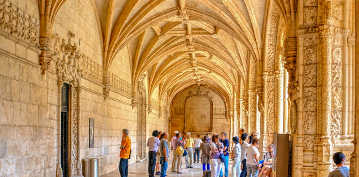Visitors exploring the ornate cloister of Jeronimos Monastery, Lisbon.