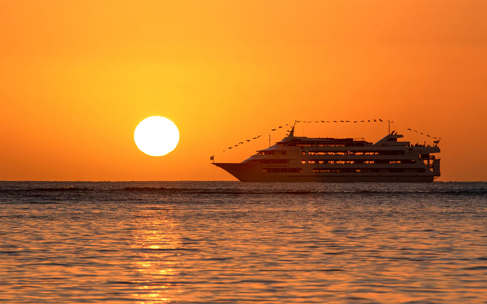 Cruise ship sailing at sunset during Star Independence Day Cruise, Hawaii.