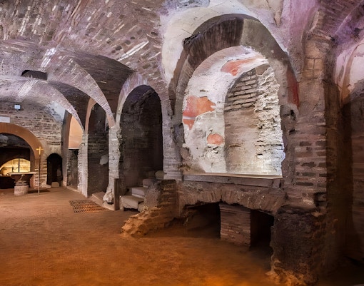 Tour guide leading a group through the historic Roman Catacombs, exploring the eerie Capuchin Crypts, and marveling at the Basilica of San Nicola on a guided tour in Rome