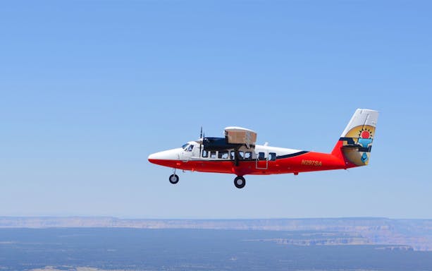Airplane flying over Grand Canyon West with clear blue sky.