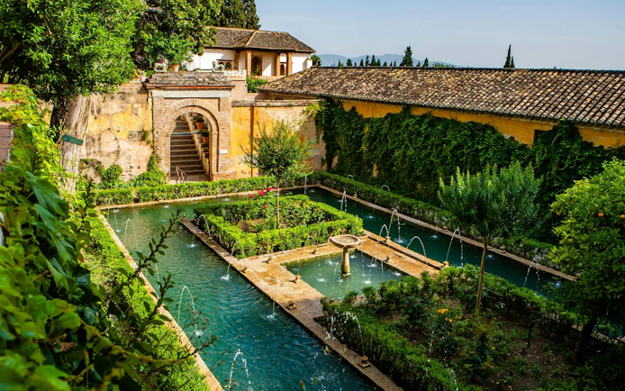 Patio de la Acequia with water channels and lush gardens in Generalife, Alhambra, Granada, Spain.