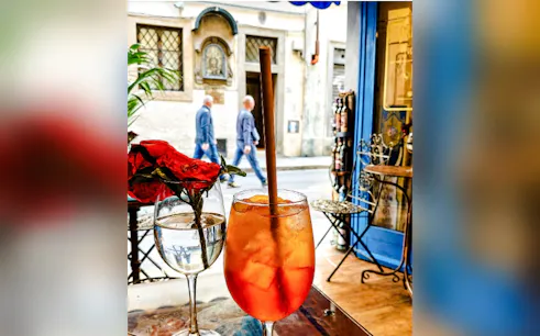 Glass of Aperol Spritz on a table in a Florentine enoteca, with street view in Rome.