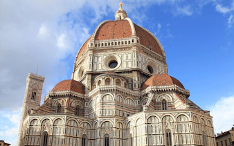 Florence Cathedral's red-tiled dome and marble facade under blue sky, part of Florence in a Day tour.