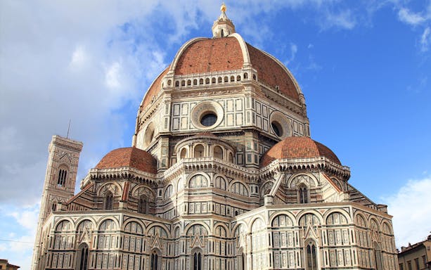 Florence Cathedral's red-tiled dome and marble facade under blue sky, part of Florence in a Day tour.