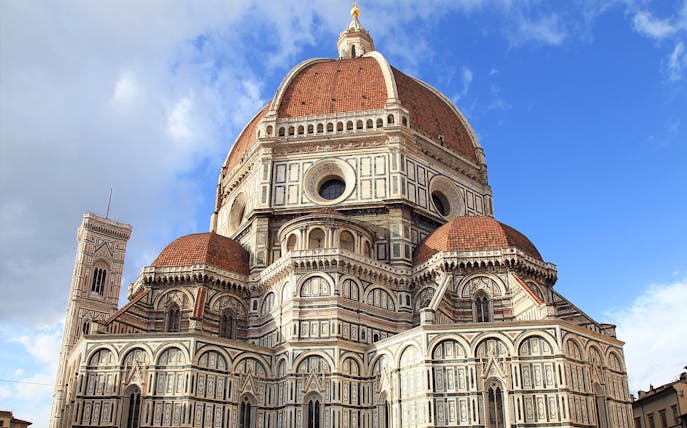 Florence Cathedral's red-tiled dome and marble facade under blue sky, part of Florence in a Day tour.
