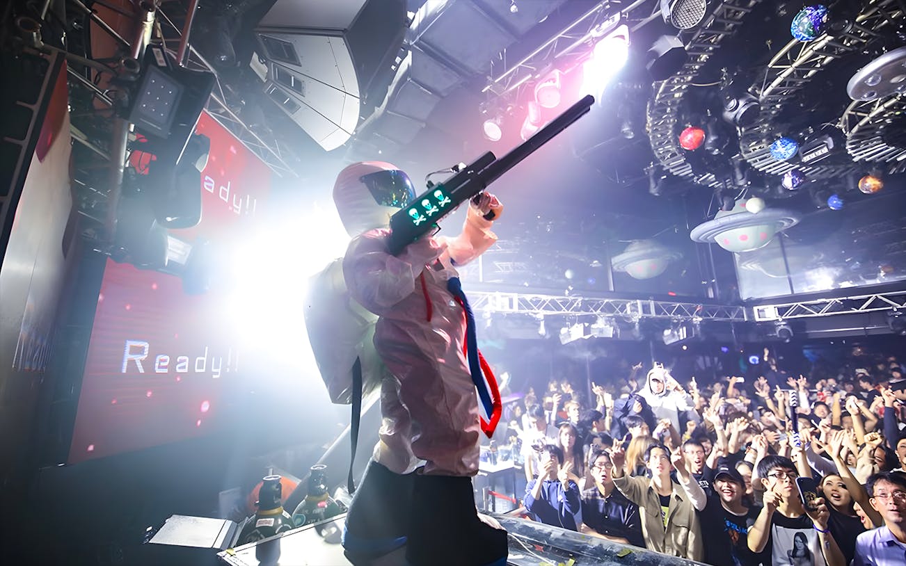 Performer in futuristic costume at WARP Shinjuku Nightclub with crowd cheering.
