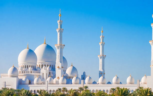 Sheikh Zayed Grand Mosque domes and minarets under clear blue sky in Abu Dhabi.