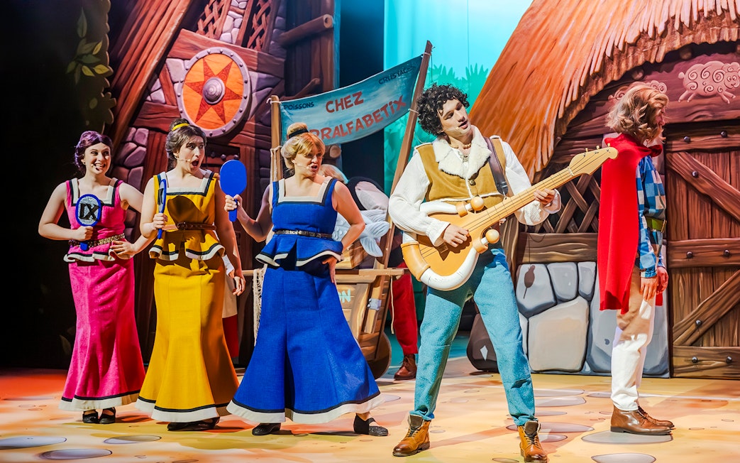 Performers in colorful costumes on stage at Parc Asterix, France.