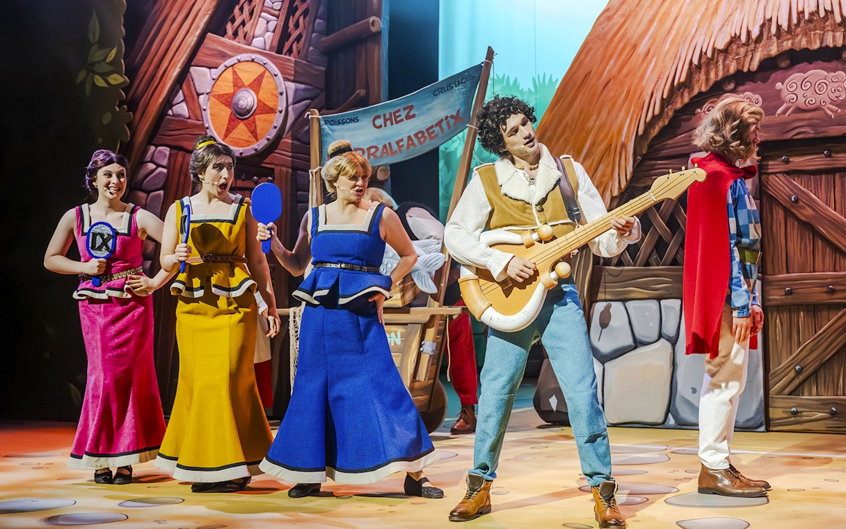 Performers in colorful costumes on stage at Parc Asterix, France.