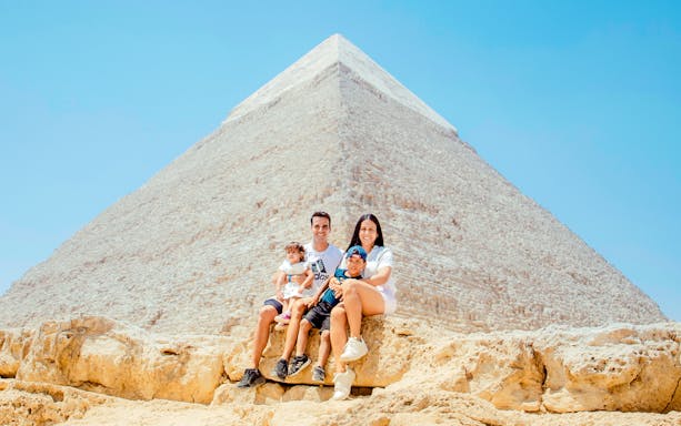 Family sitting in front of the Pyramid of Giza, Egypt.