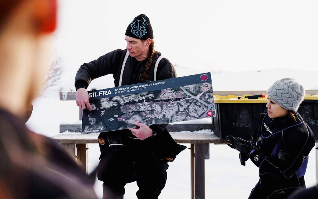 Tour guide explaining Silfra Snorkeling route to guests with a map in Iceland.