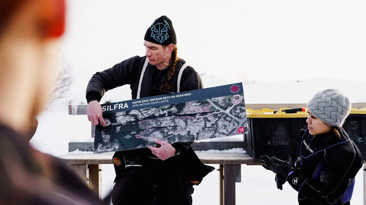 Tour guide explaining Silfra Snorkeling route to guests with a map in Iceland.