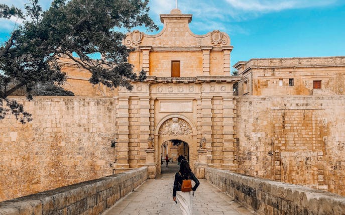 Entrance to Mdina, Malta with a visitor walking through the historic city gate.