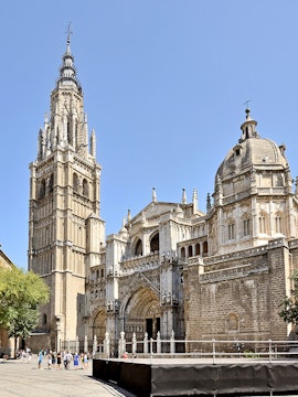 Toledo Cathedral facade with bell tower under clear sky.