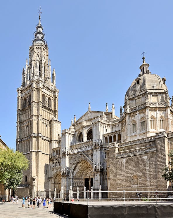 Toledo Cathedral facade with bell tower under clear sky.