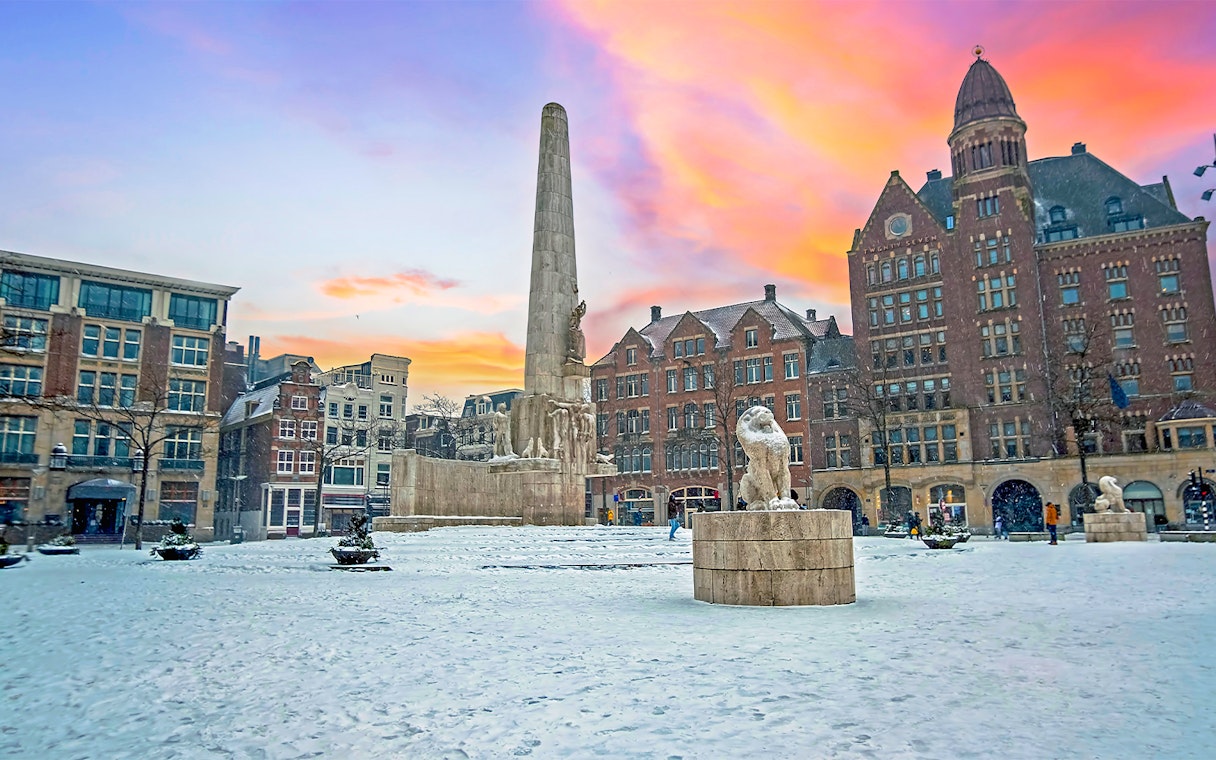 National Monument in snowy Dam Square, Amsterdam at sunset.