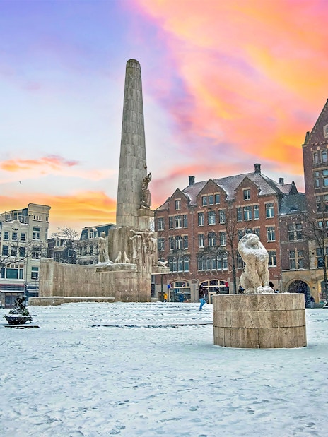 National Monument in snowy Dam Square, Amsterdam at sunset.