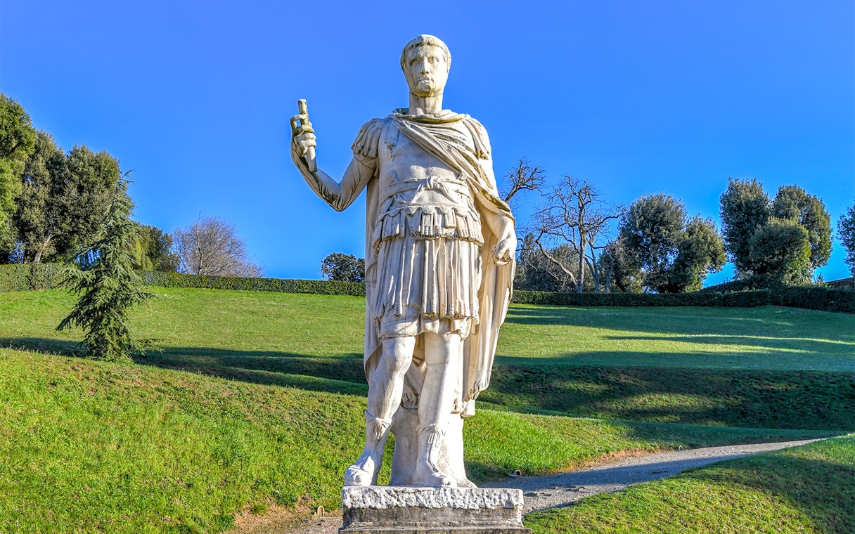 Statue of a Roman figure holding a scroll in Boboli Gardens, Florence.