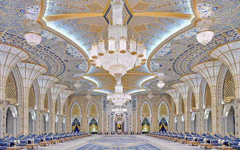 Grand hall with ornate chandeliers and intricate ceiling design in Abu Dhabi, part of a private city tour from Dubai.