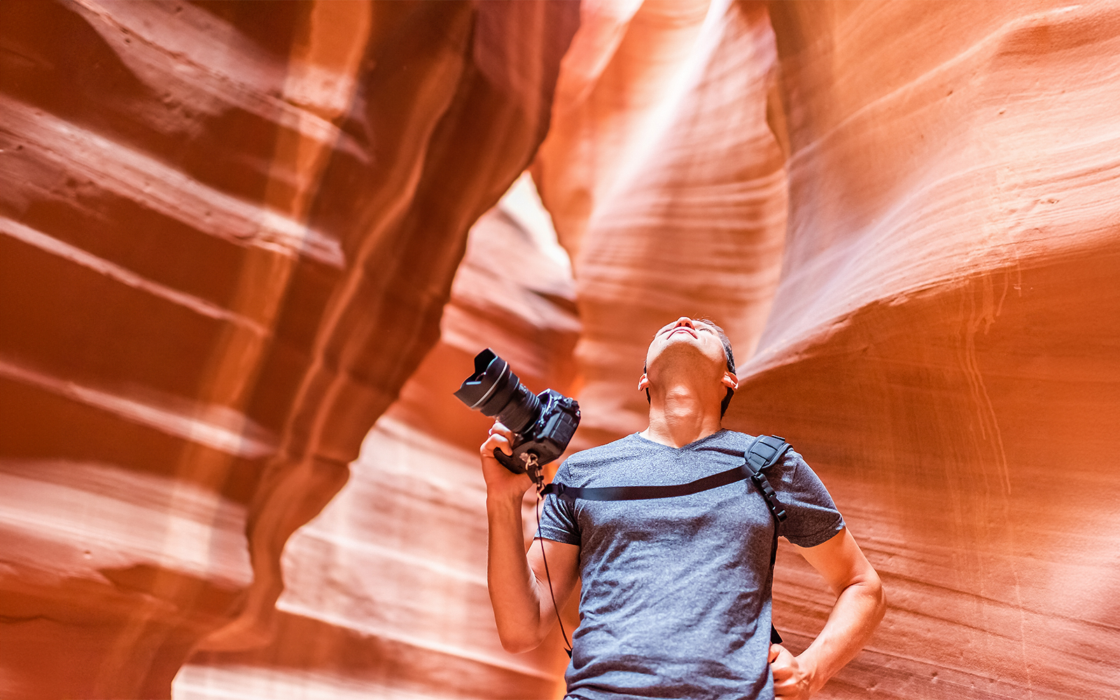 Tourist with camera exploring Lower Antelope Canyon's narrow pathways in Arizona.