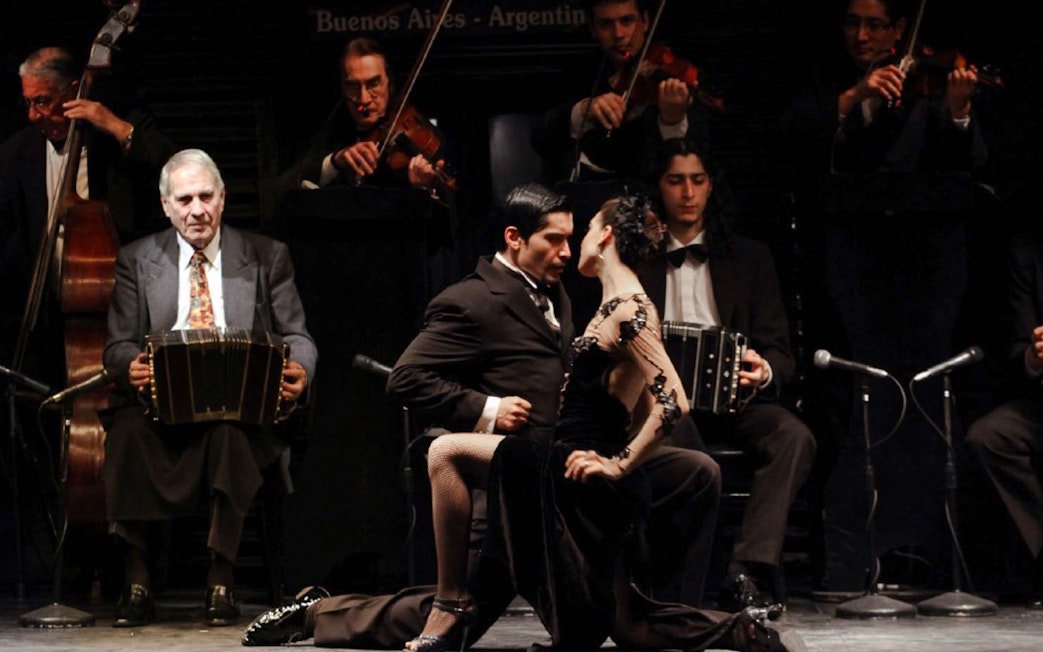 Dancers performing at Piazzolla Tango Show in Buenos Aires with live musicians.