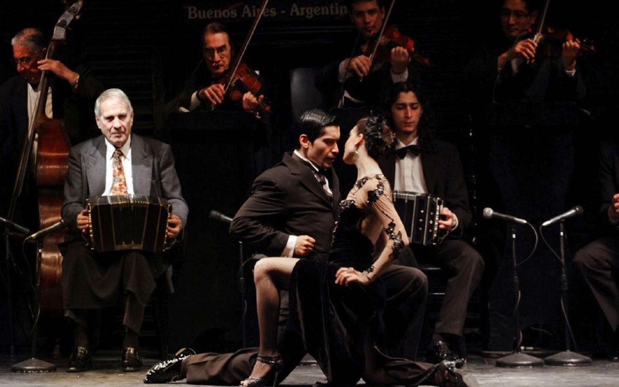 Dancers performing at Piazzolla Tango Show in Buenos Aires with live musicians.