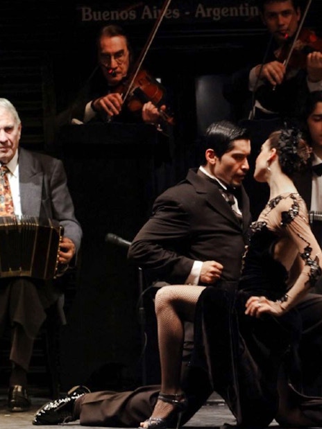 Dancers performing at Piazzolla Tango Show in Buenos Aires with live musicians.