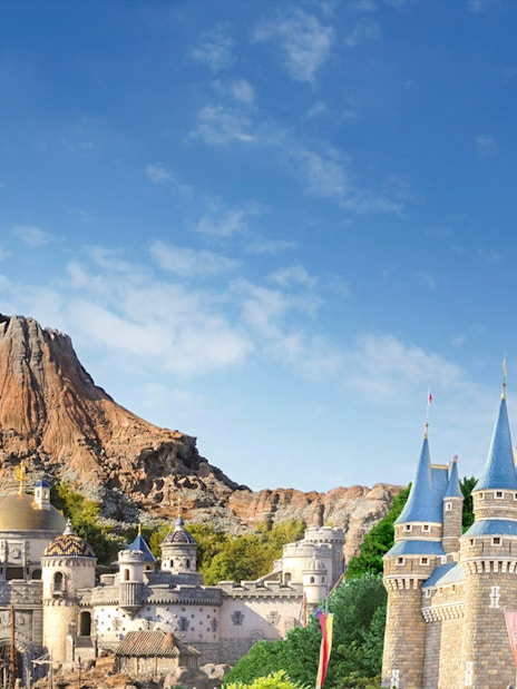 Tokyo DisneySea's Mount Prometheus and Cinderella Castle under a clear blue sky.