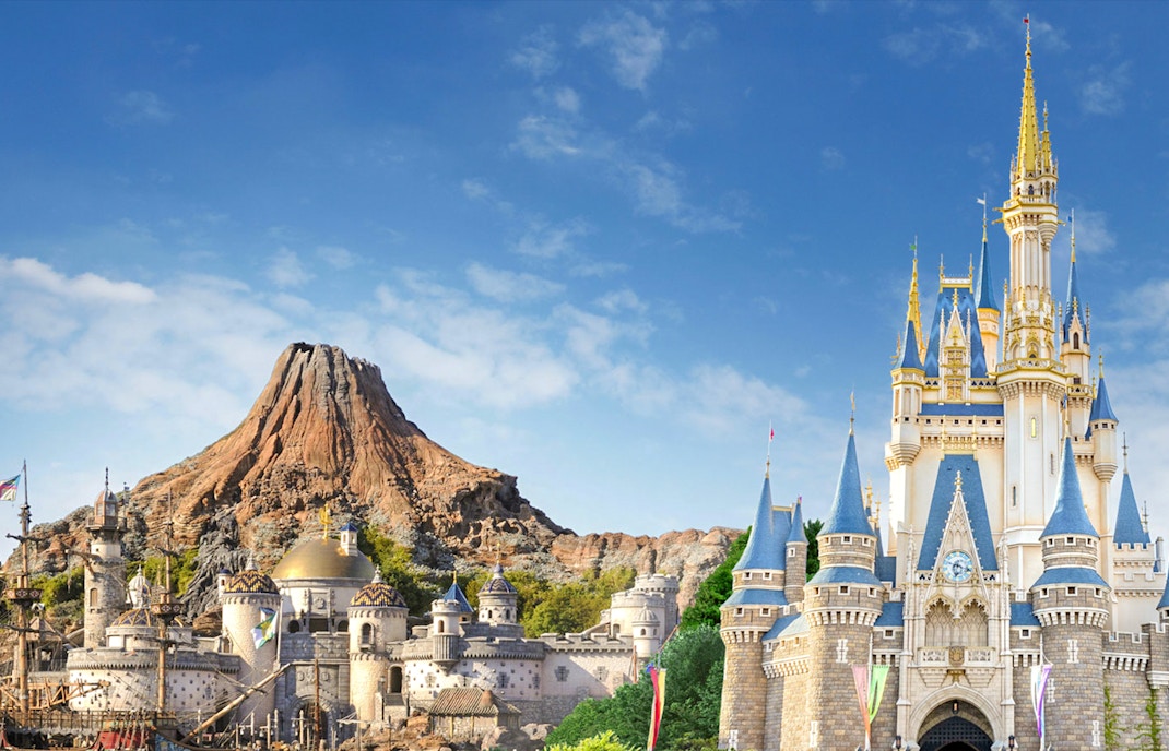 Visitors enjoying attractions at Tokyo DisneySea with iconic Mount Prometheus in the background.