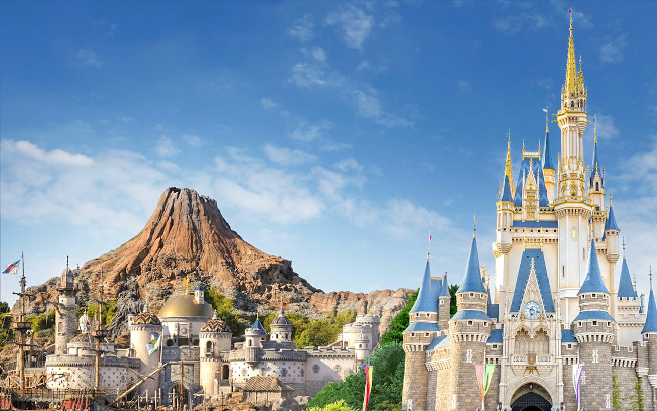 Tokyo DisneySea's Mount Prometheus and Cinderella Castle under a clear blue sky.