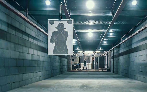 Shooting target in indoor range with person aiming in background, Warsaw.