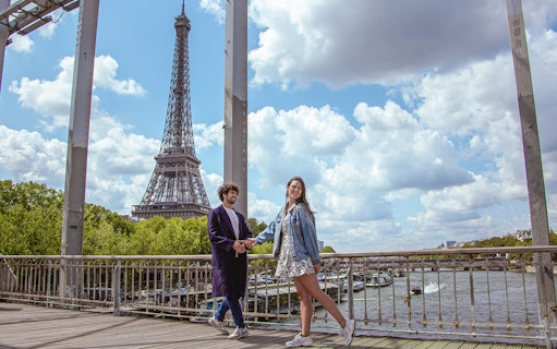 Couple posing on a bridge with the Eiffel Tower in the background, Paris.
