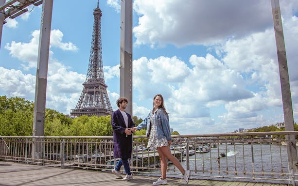 Couple posing on a bridge with the Eiffel Tower in the background, Paris.