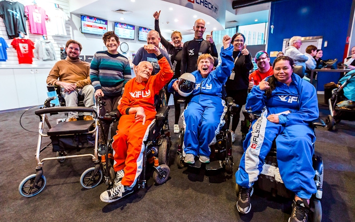 Group of people in wheelchairs celebrating at iFLY Indoor Skydiving Experience.