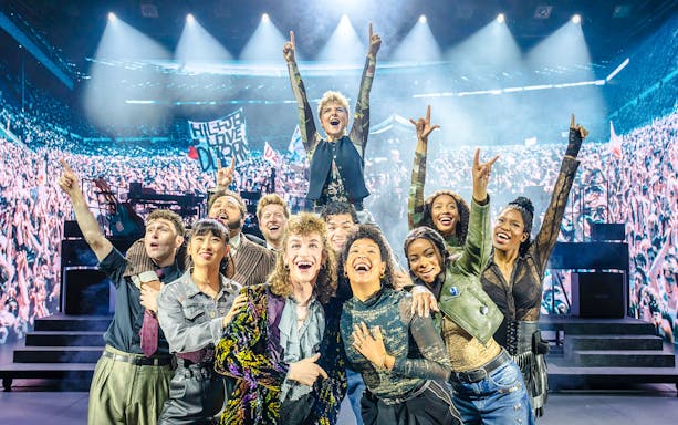 Performers on stage at Just for One Day concert with cheering crowd.