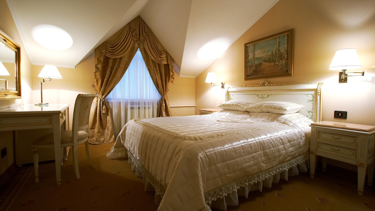 Luxury hotel room with king-sized bed, modern decor, and large windows in Paris, France.