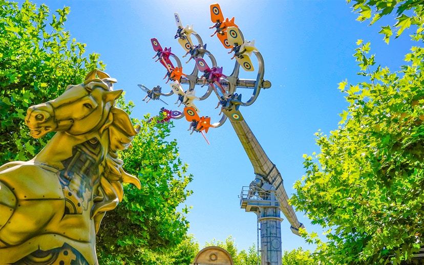 Sky Fighter ride at The Land of Legends theme park with colorful planes and a golden horse statue.