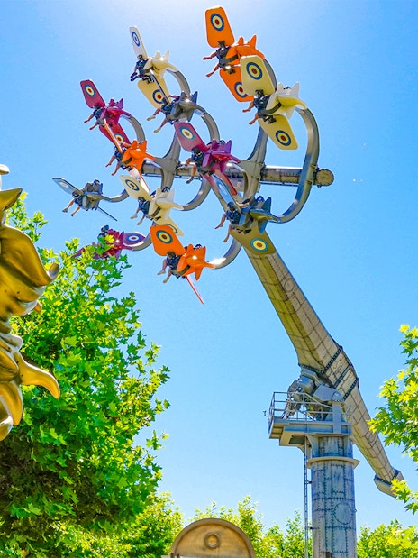 Sky Fighter ride at The Land of Legends theme park with colorful planes and a golden horse statue.
