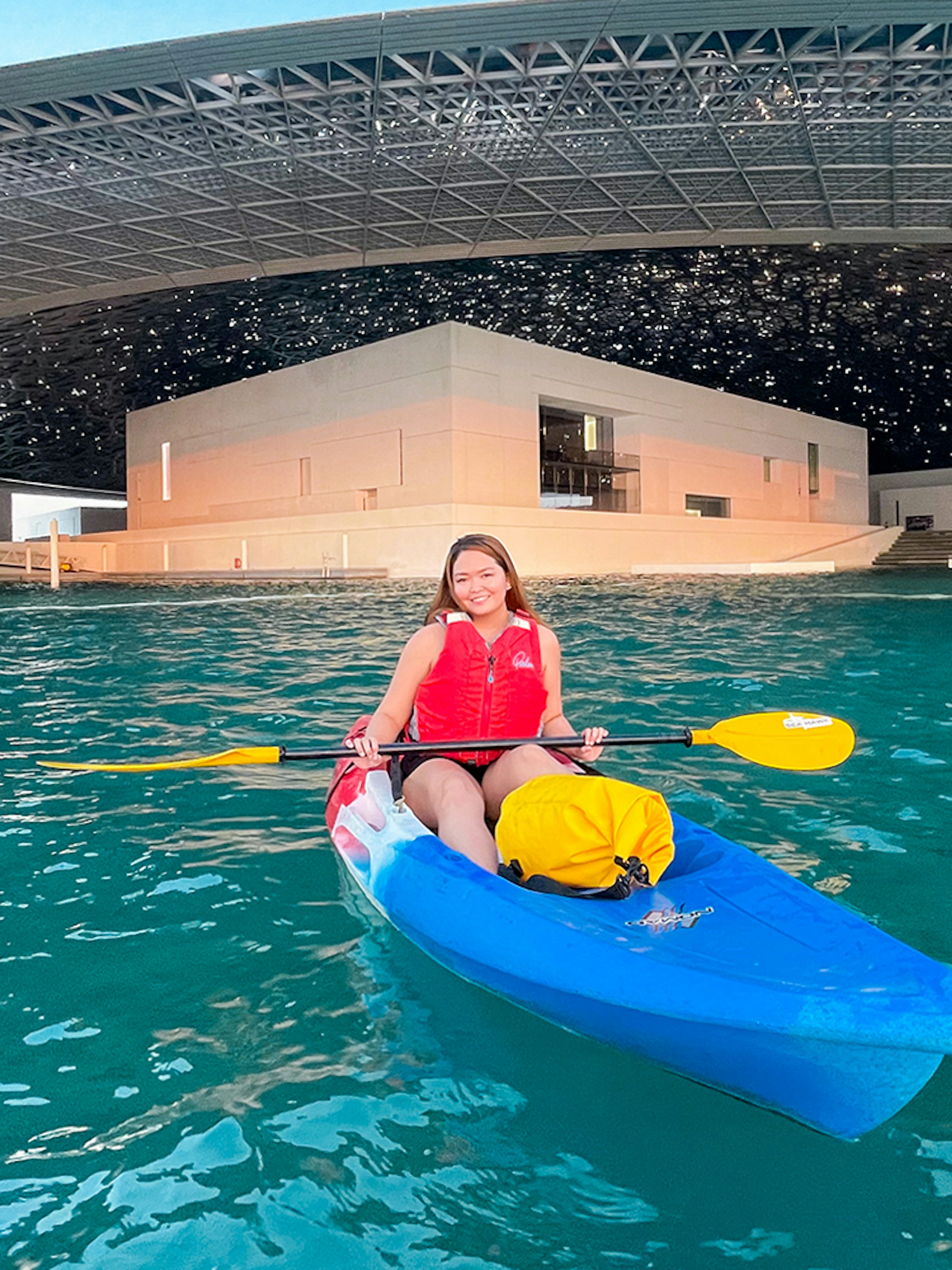 Kayaker paddling near Louvre Abu Dhabi's unique architecture.