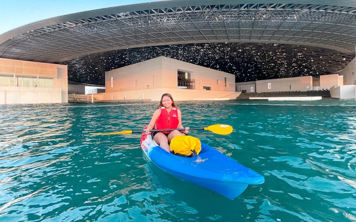 Kayaker paddling near Louvre Abu Dhabi's unique architecture.