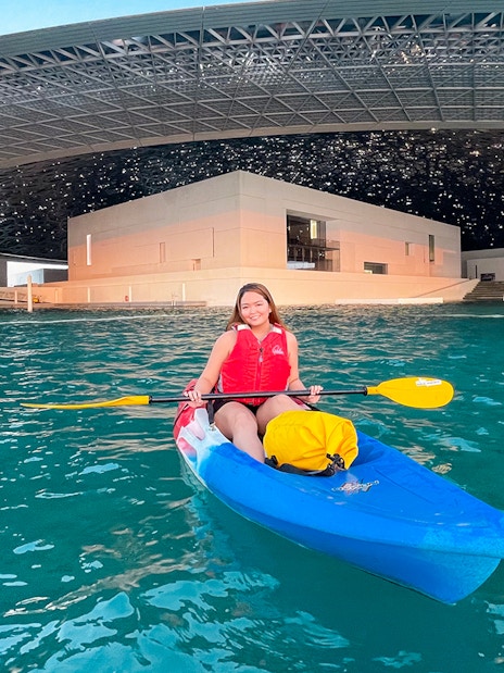 Kayaker paddling near Louvre Abu Dhabi's unique architecture.