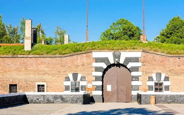 Entrance gate of Terezin concentration camp, Czech Republic, with brick walls and greenery.