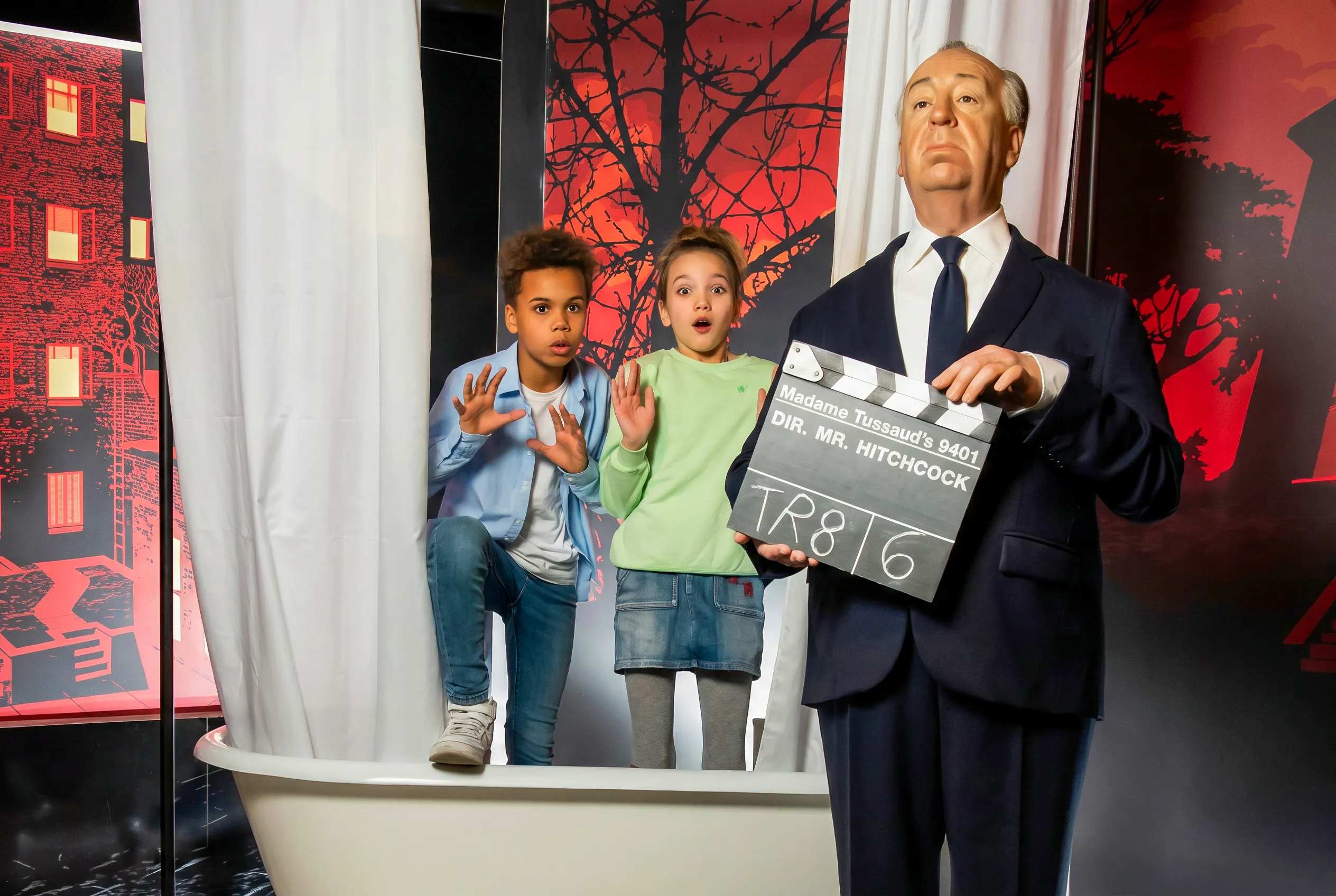Children posing with Hitchcock figure at Madame Tussauds Vienna.