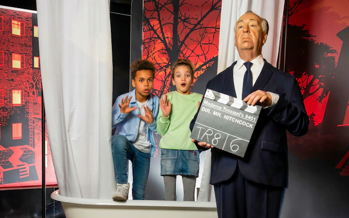 Children posing with Hitchcock figure at Madame Tussauds Vienna.