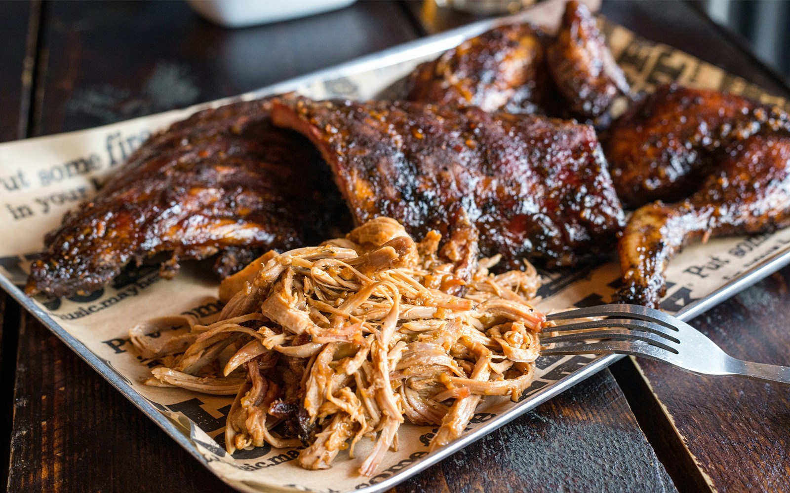 Pork ribs with barbecue sauce served on a wooden platter in a restaurant.
