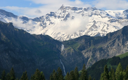 Helicopter view of the Matterhorn with snow-capped peaks and a waterfall in Switzerland.