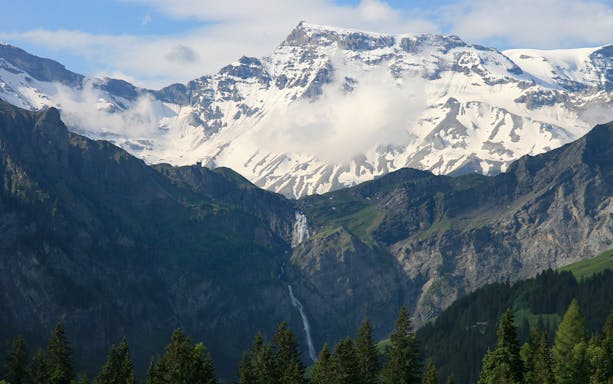 Helicopter view of the Matterhorn with snow-capped peaks and a waterfall in Switzerland.
