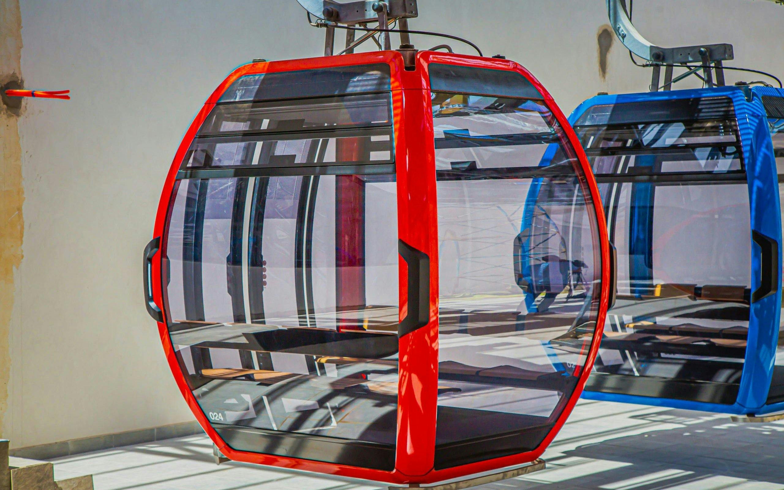 Red and blue cable cars at a station for night round-trip ticket experience.