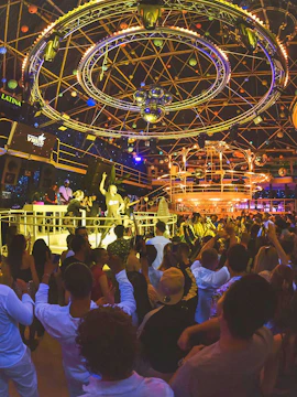 Crowded dance floor at Vibes Party, Es Paradis, with vibrant lighting and DJ booth.